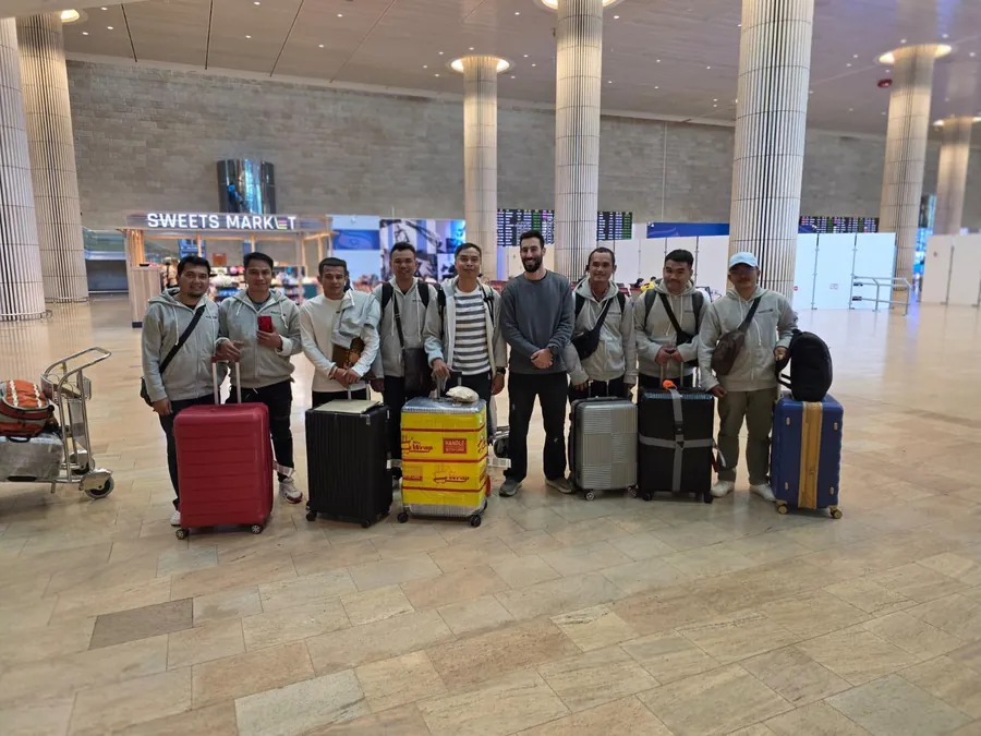 עובדים זרים עם מזוודות באולם הנוסעים הנכנסים בנתב