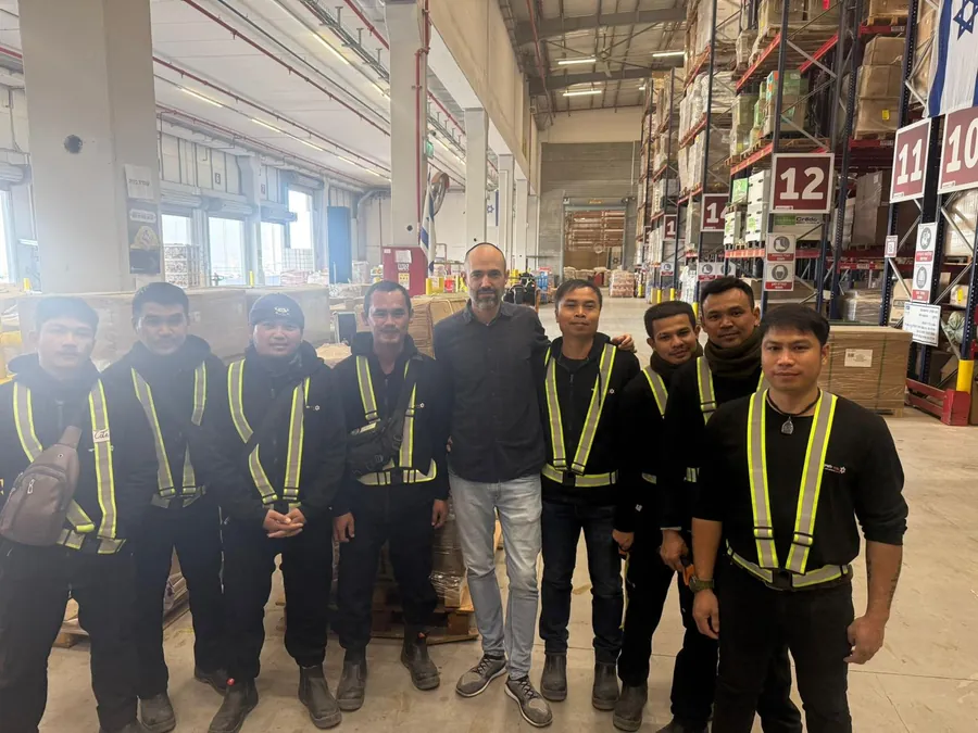 צוות עובדים זרים במחסן לוגיסטי בישראל עם נציג ARO Group